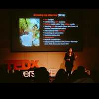 A person delivers a lecture. Behind them is a TedX logo and a lecture screen 'reading 'Growing Up Married' 2016'