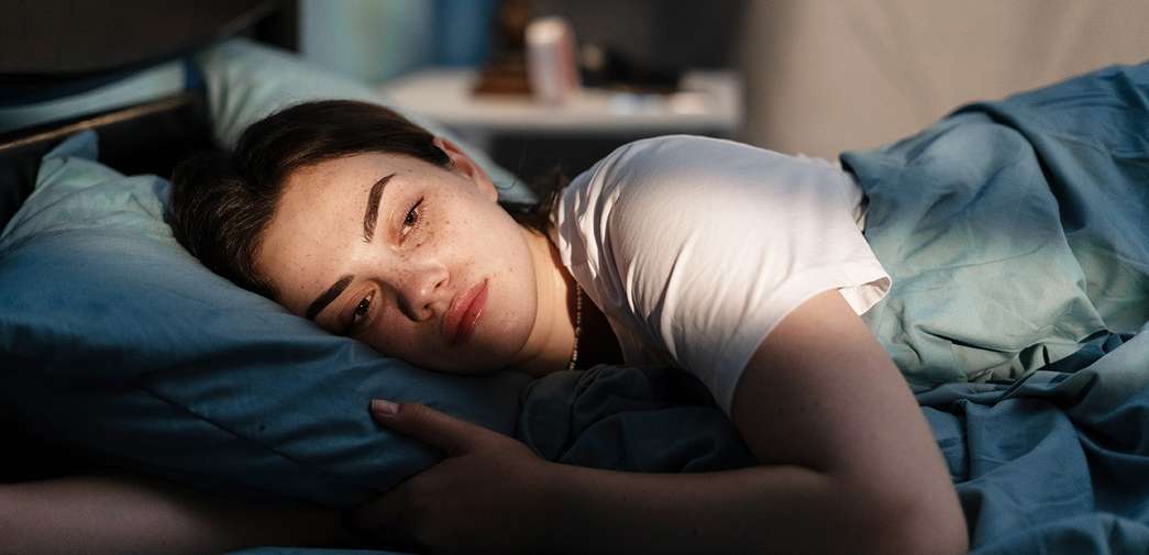 A woman lying in bed awake.