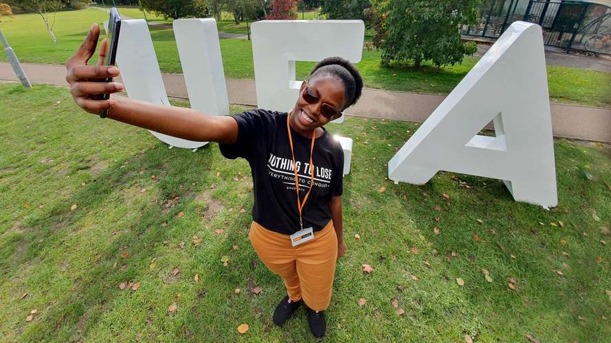 Image of student taking a selfie infront of UEA letters