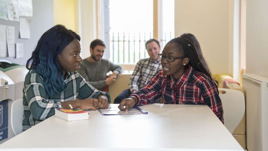 Students chatting at table at Barton and Hickling, en-suite accommodation with open plan kitchen/diner and oven