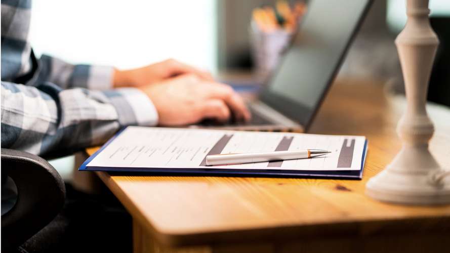 student with an application form and a laptop