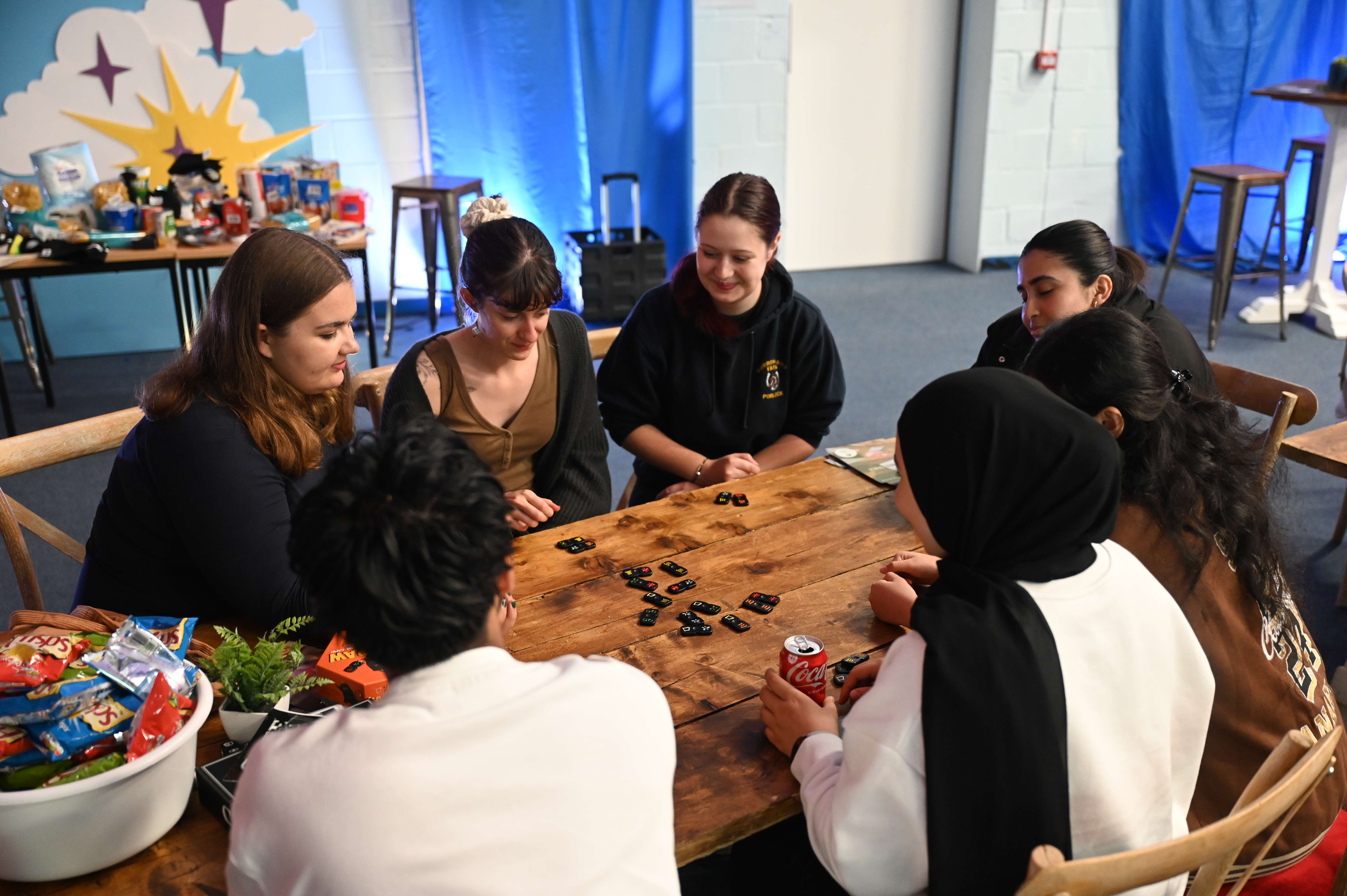 A group of students sit around a table playing a game together.