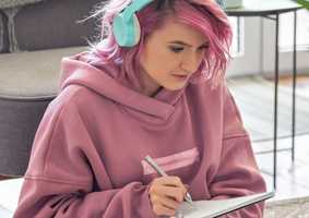student wearing headphones writing on notepad