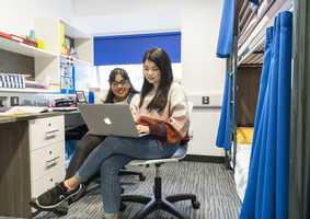 students looking at laptop together in two bunk bed room