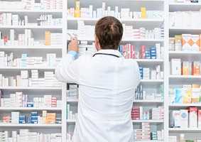 Pharmacist looking at shelves of medicine