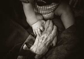Elderly person and baby holding hands